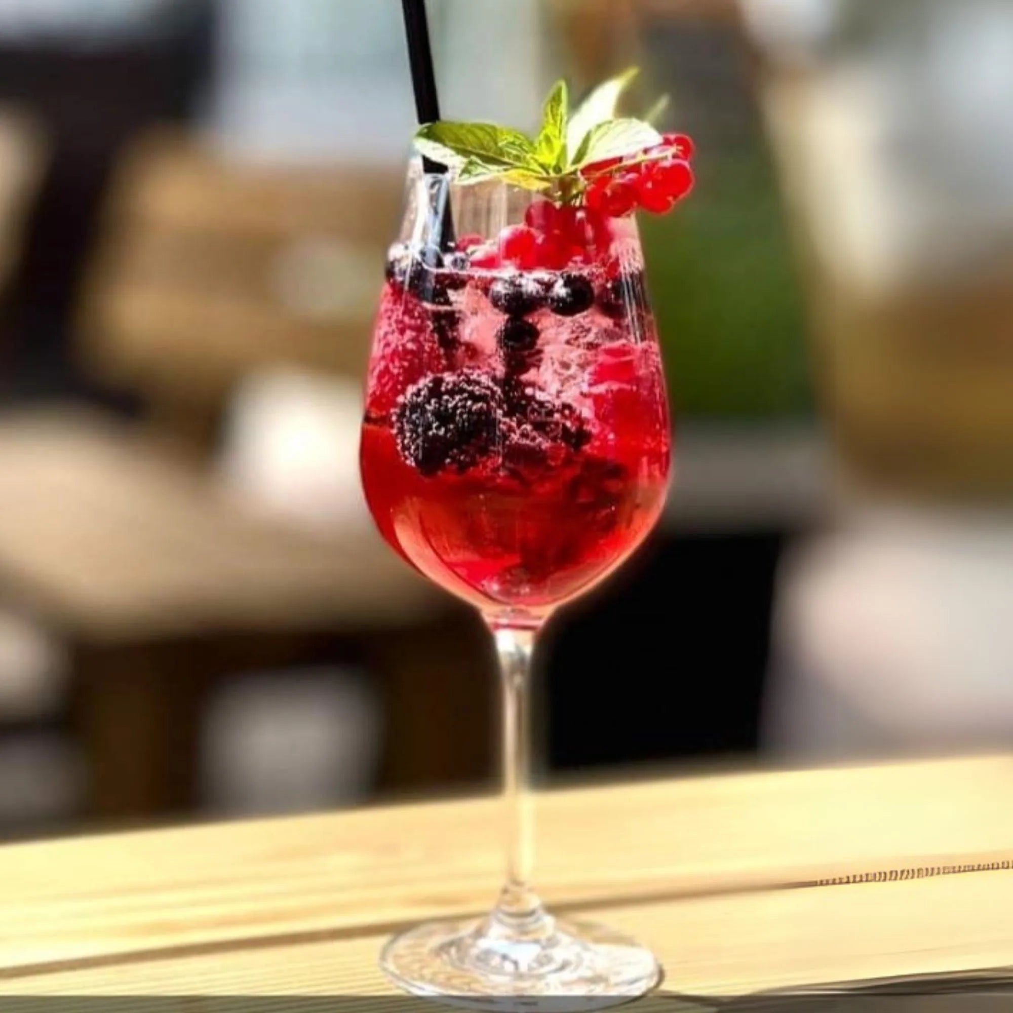Eleganter Aperitif mit Solivér Brombeer Gin-Likör, serviert im Weinglas mit Brombeeren, Johannisbeeren, Minze und Eiswürfeln.