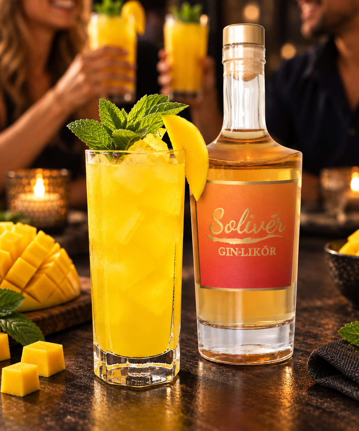 Solivér Mango Gin-Likör neben einem erfrischenden gelben Mango-Cocktail mit frischer Minze und Mangoscheibe auf einem Holztisch in gemütlicher Atmosphäre.