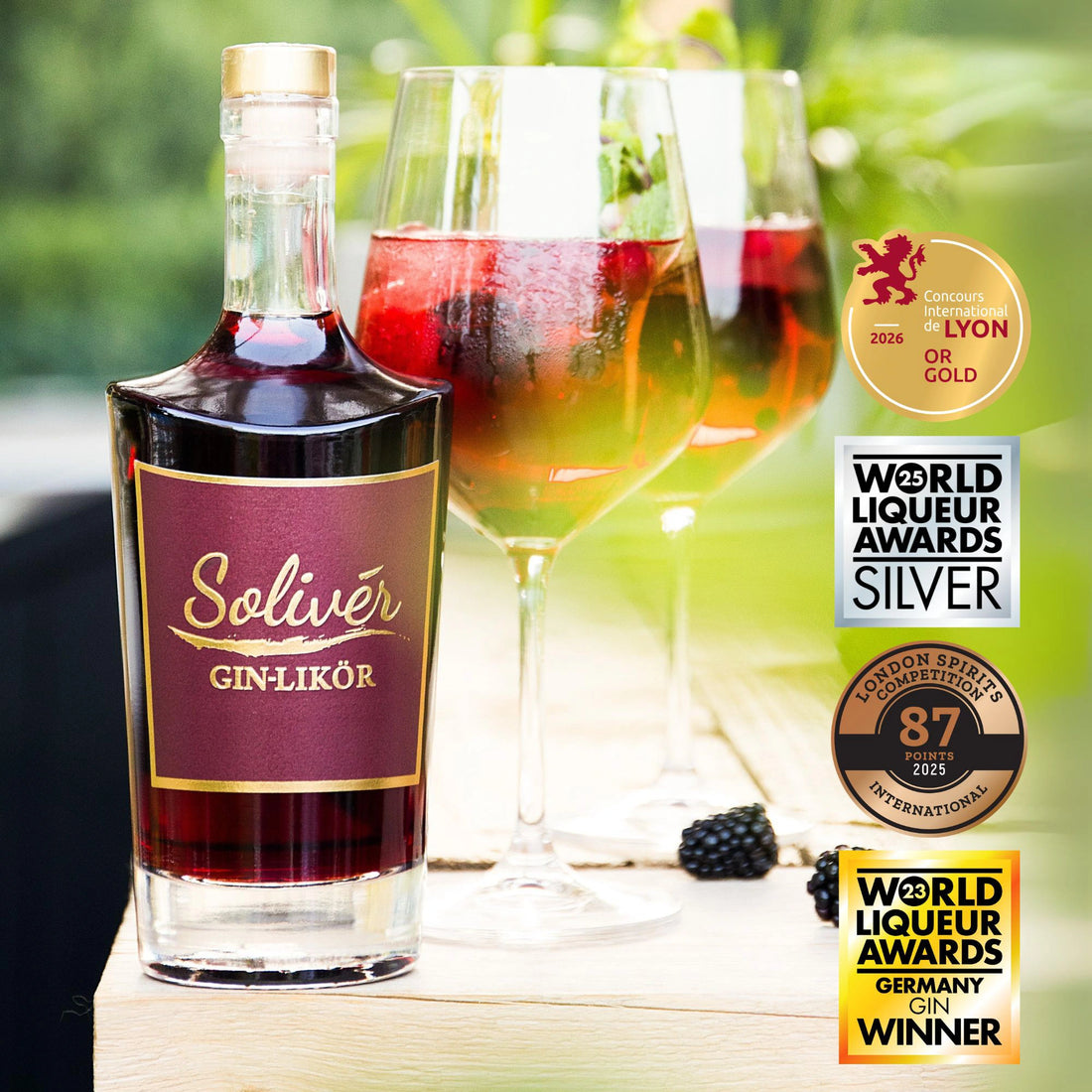 Solivér Brombeer Gin-Likör in eleganter Flasche, serviert auf Eis mit frischen Beeren in Weingläsern – sommerlicher Genuss im Freien“