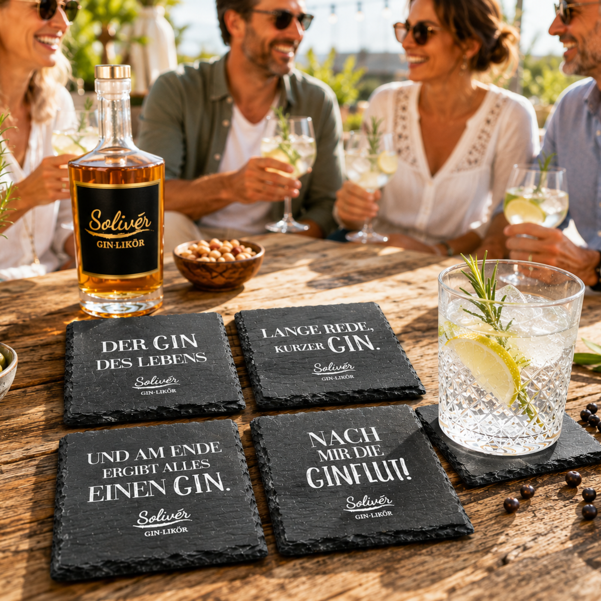 Solivér Gin-Likör Flasche und schwarze Schiefer-Untersetzer mit humorvollen Gin-Sprüchen auf einem Holztisch. Im Hintergrund sitzen vier Freunde bei einem sonnigen Abend zusammen und genießen ihre Drinks.
