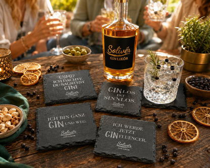 Solivér Gin-Likör Flasche mit einem Gin-Drink auf einem Holztisch, umgeben von schwarzen Schiefer-Untersetzern mit humorvollen Gin-Sprüchen, getrockneten Orangen, Wacholderbeeren und Snacks. Im Hintergrund sitzen Freunde gemeinsam bei ihren Drinks.